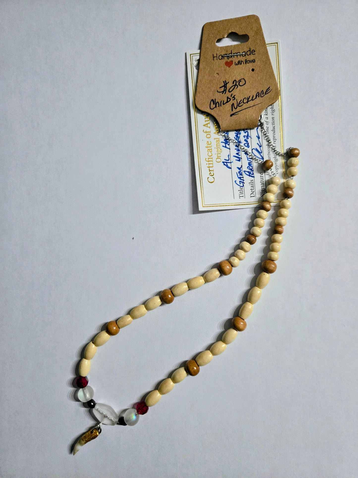 Handmade beaded necklace with multicolored wooden beads, accented with frosted spacer beads, and having a Genuine Alligator Tooth pendant as the focal point. This necklace is sized for a child.
