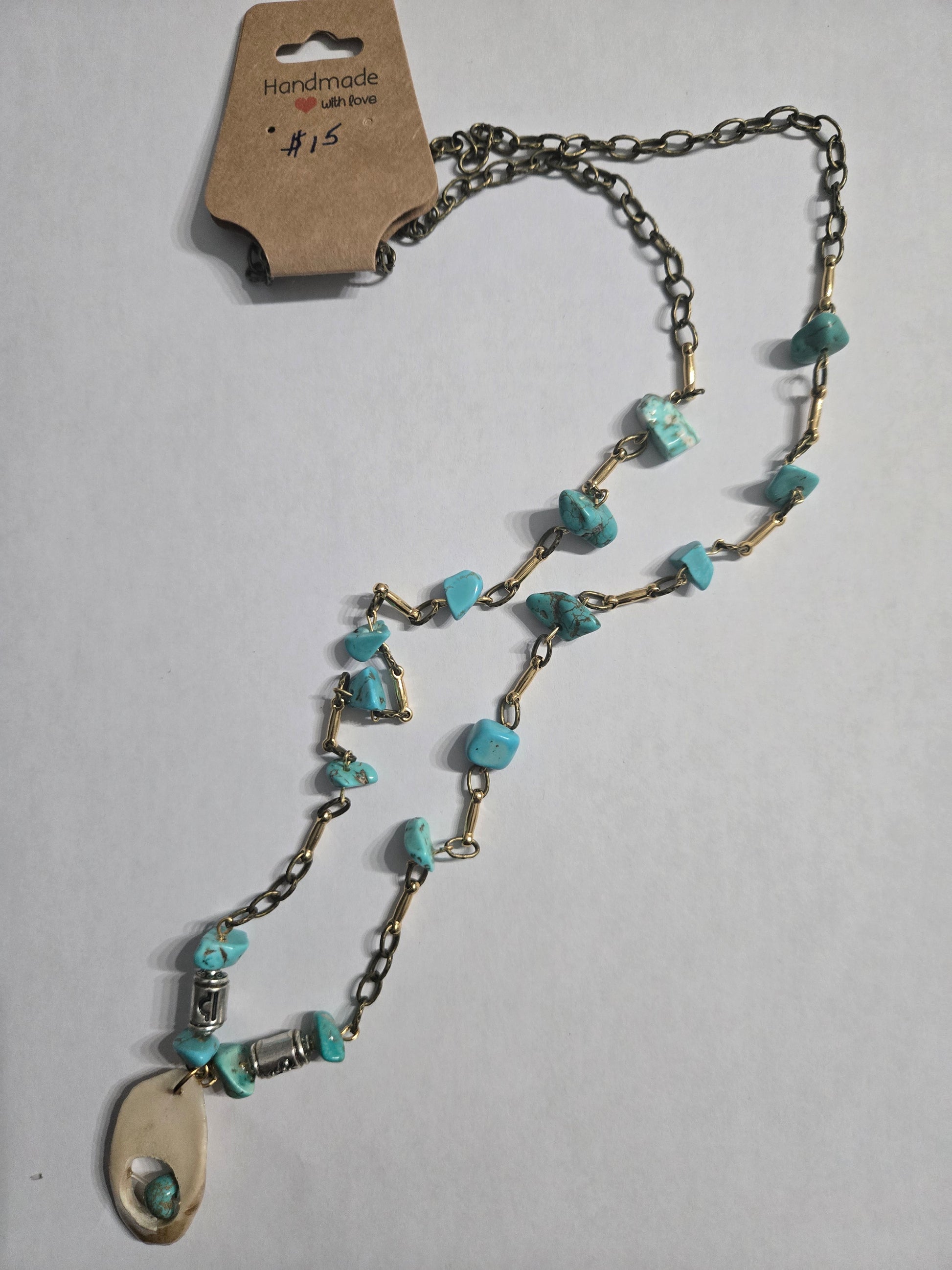 A pewter link chain necklace with gold colored spacer charms and turquoise stone charms, accented with a deer antler charm pendant as the focal point.