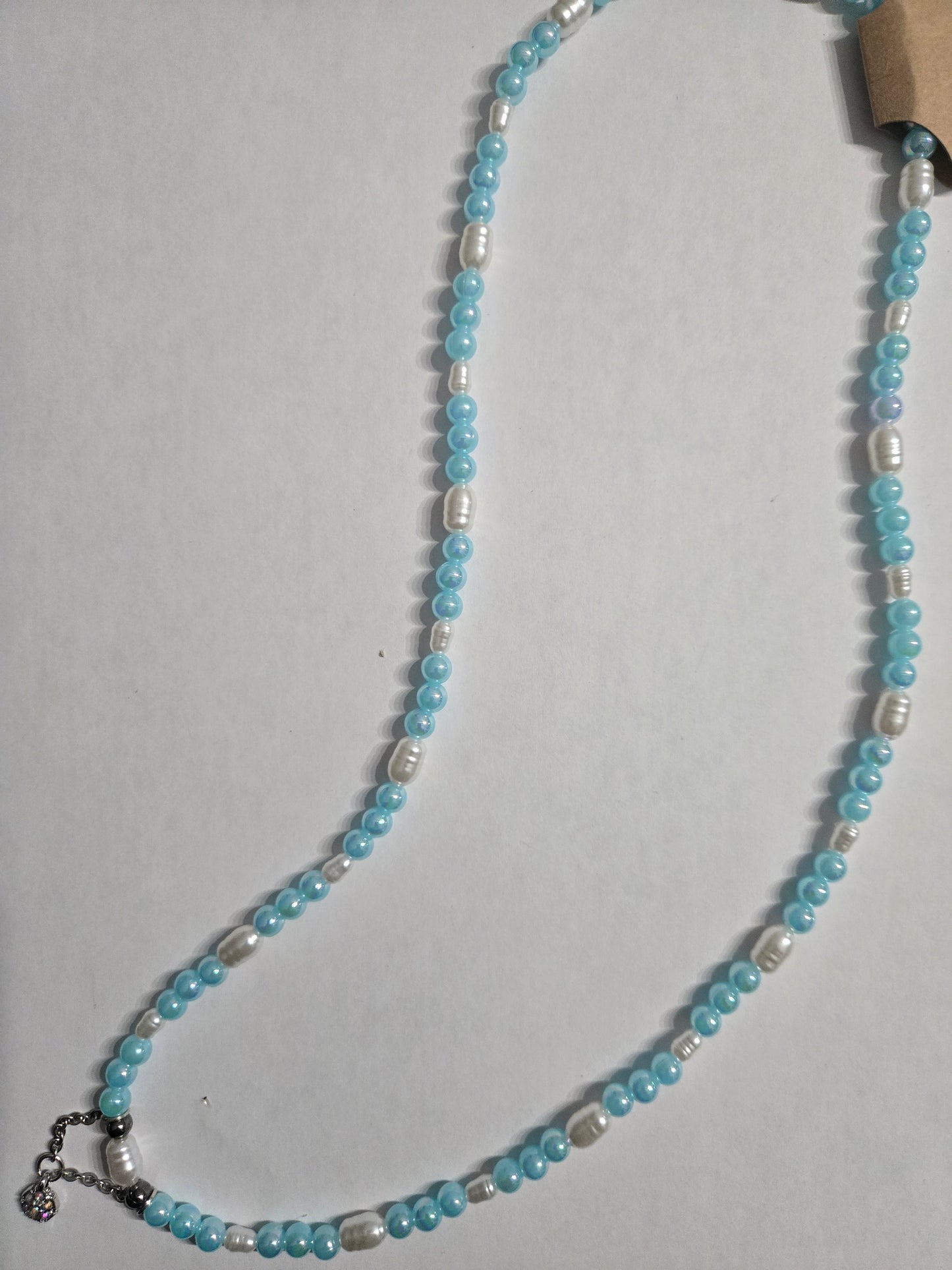 Handmade beaded necklace with light blue beads mixed with imitation pearl beads, and having a simulated CZ pendant as the focal point.
