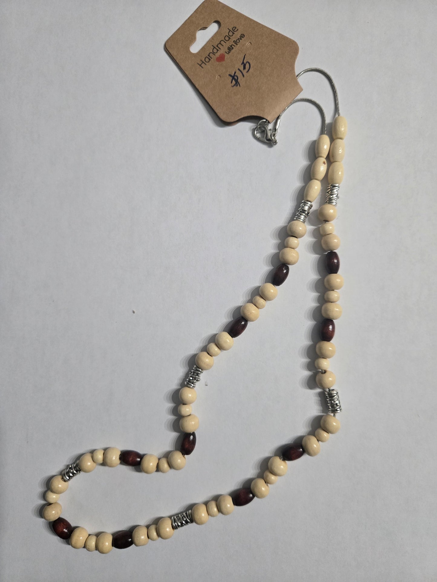 Handmade beaded necklace with multicolored wooden beads, accented with silver in color metal spacer beads, on a sterling silver chain.