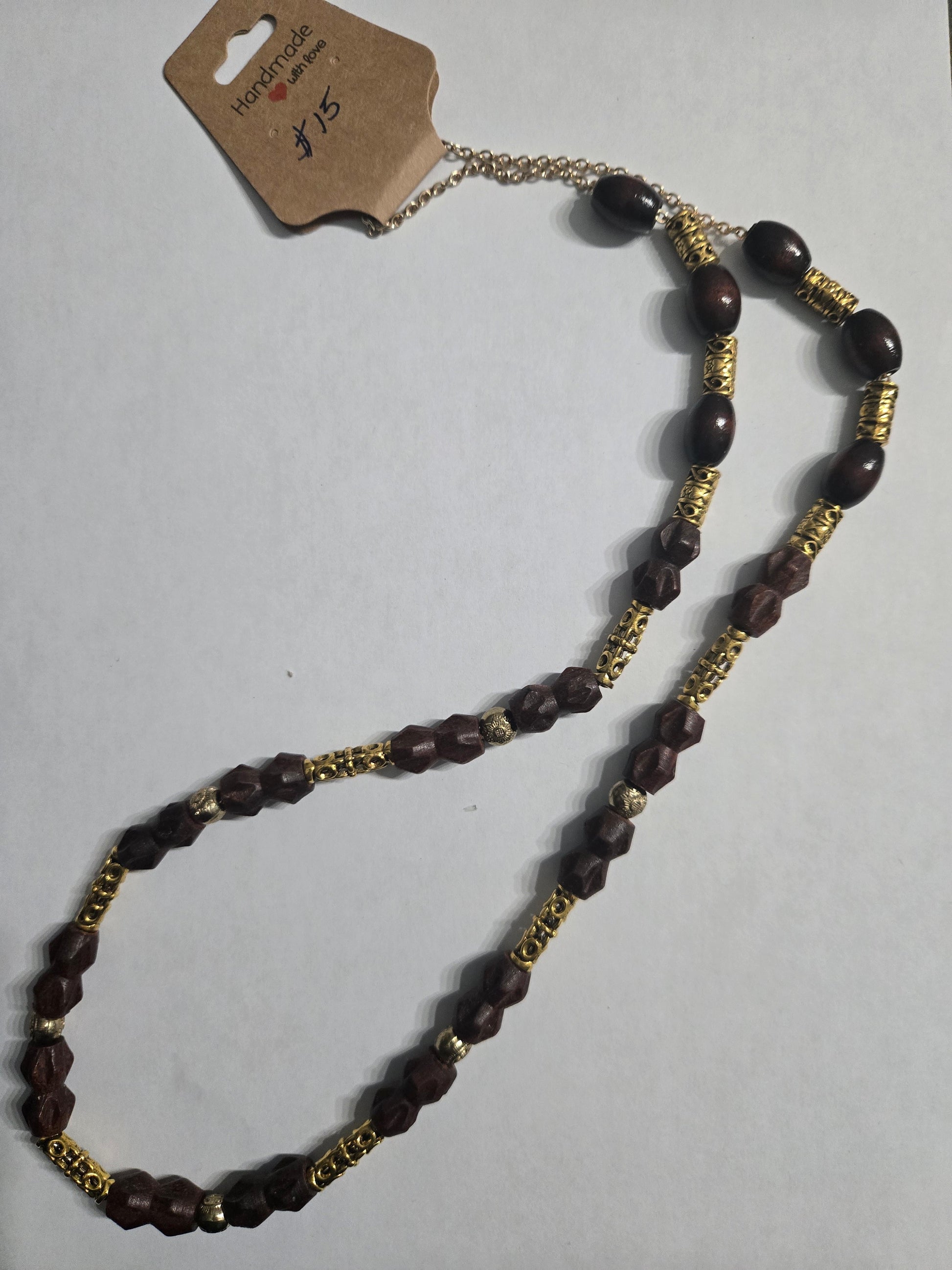 Handmade beaded necklace with brown wooden beads, and highlighted with gold in color metal spacer beads, on a gold in color chain.