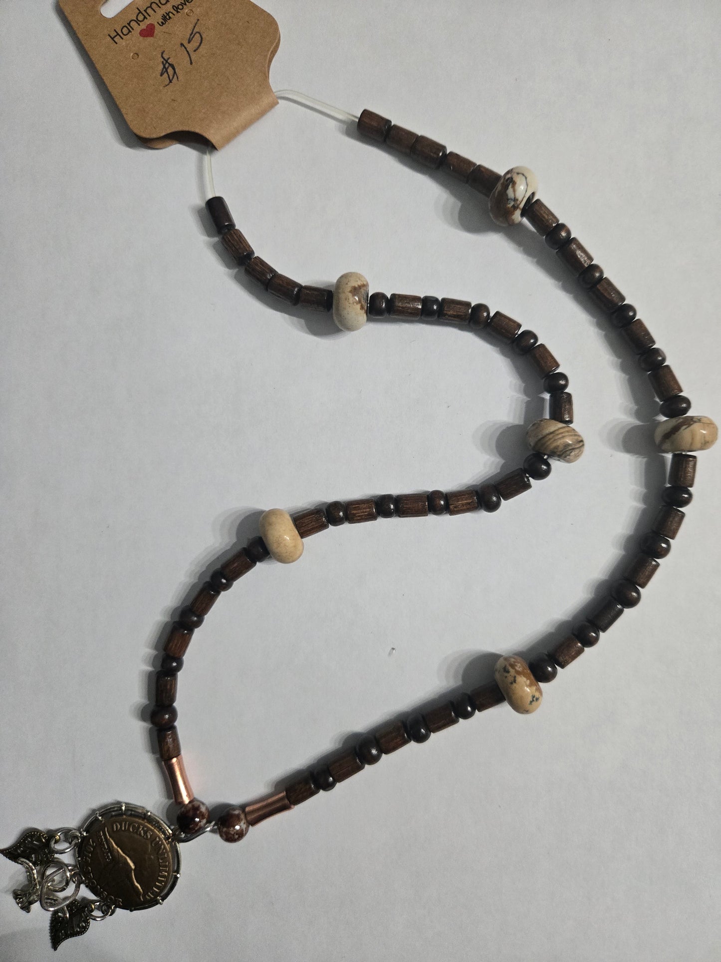 Handmade beaded necklace with brown and tan wooden beads, and featuring a Ducks Unlimited Bronze Sponsor pendant with feather charms as a focal point.
