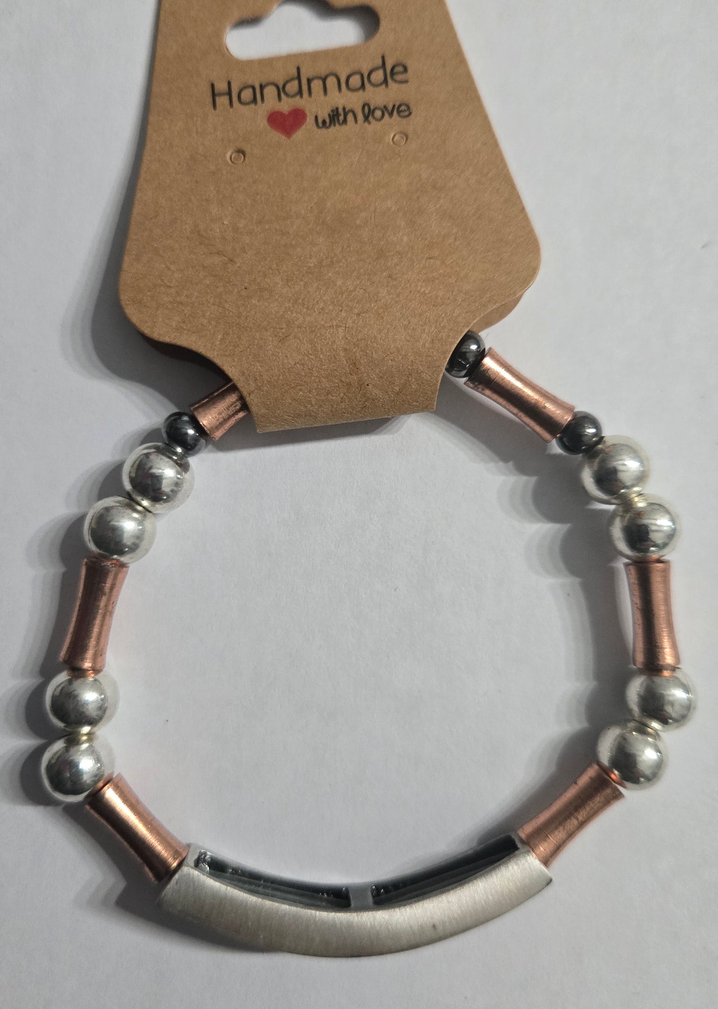Bracelet with metal beads and brass spacer beads, accented with a large charm and the word "COURAGE".