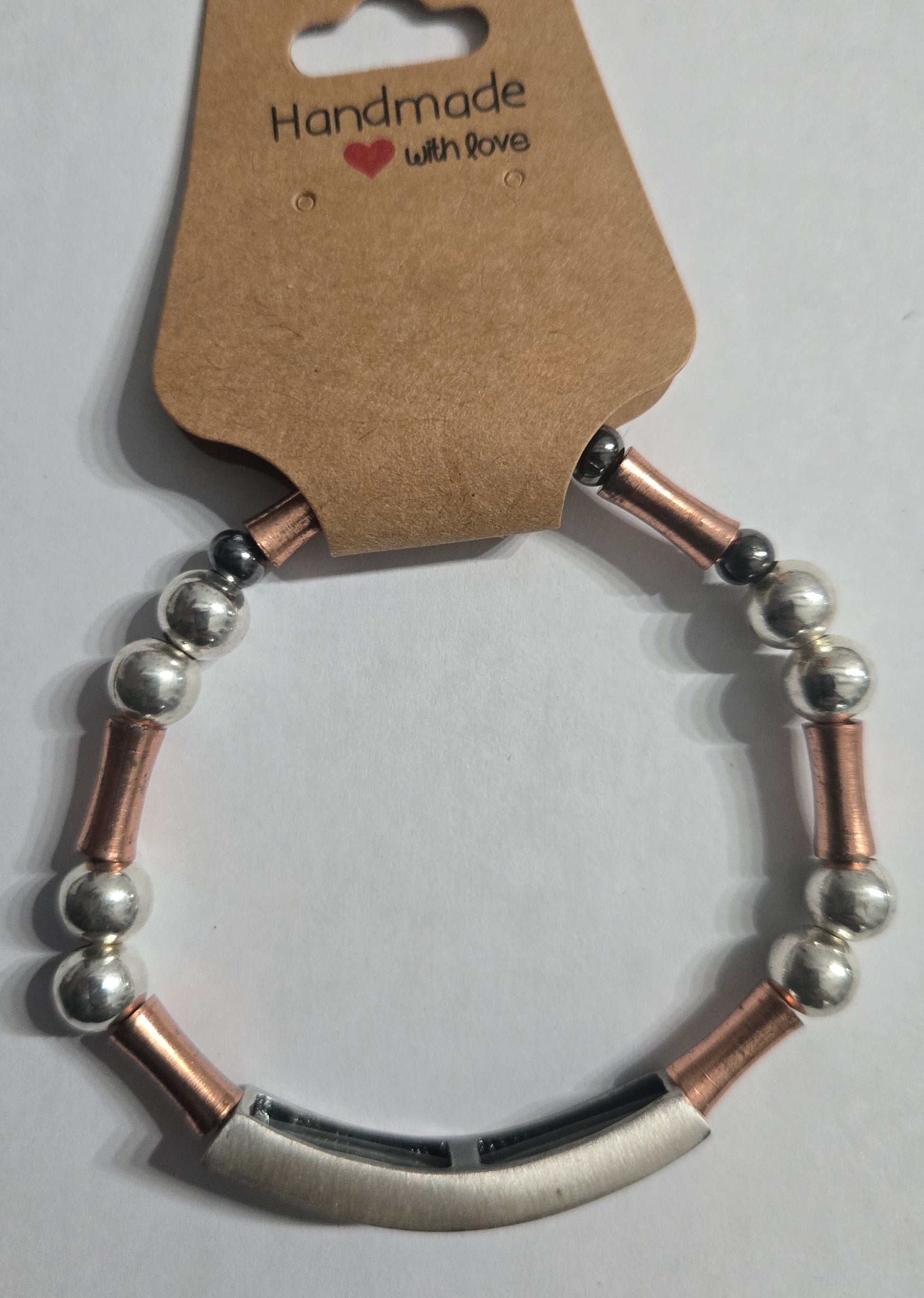 Bracelet with metal beads and brass spacer beads, accented with a large charm and the word "COURAGE".
