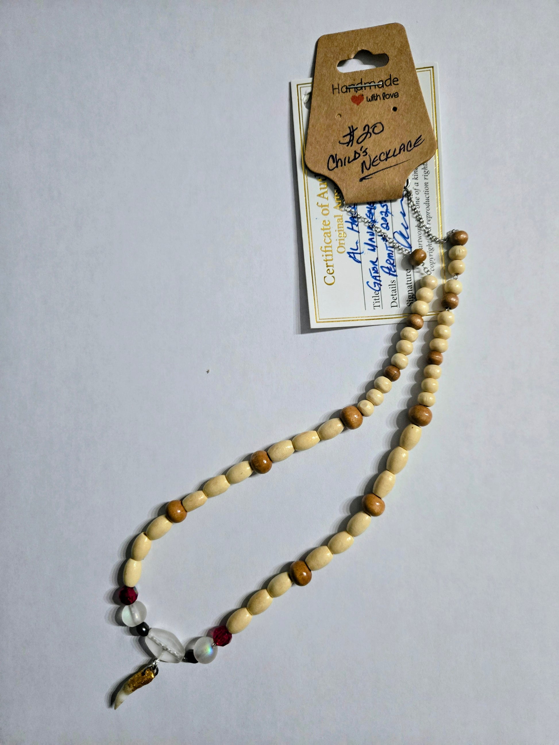 Handmade beaded necklace with multicolored wooden beads, accented with frosted spacer beads, and having a Genuine Alligator Tooth pendant as the focal point.  This necklace is sized for a child.