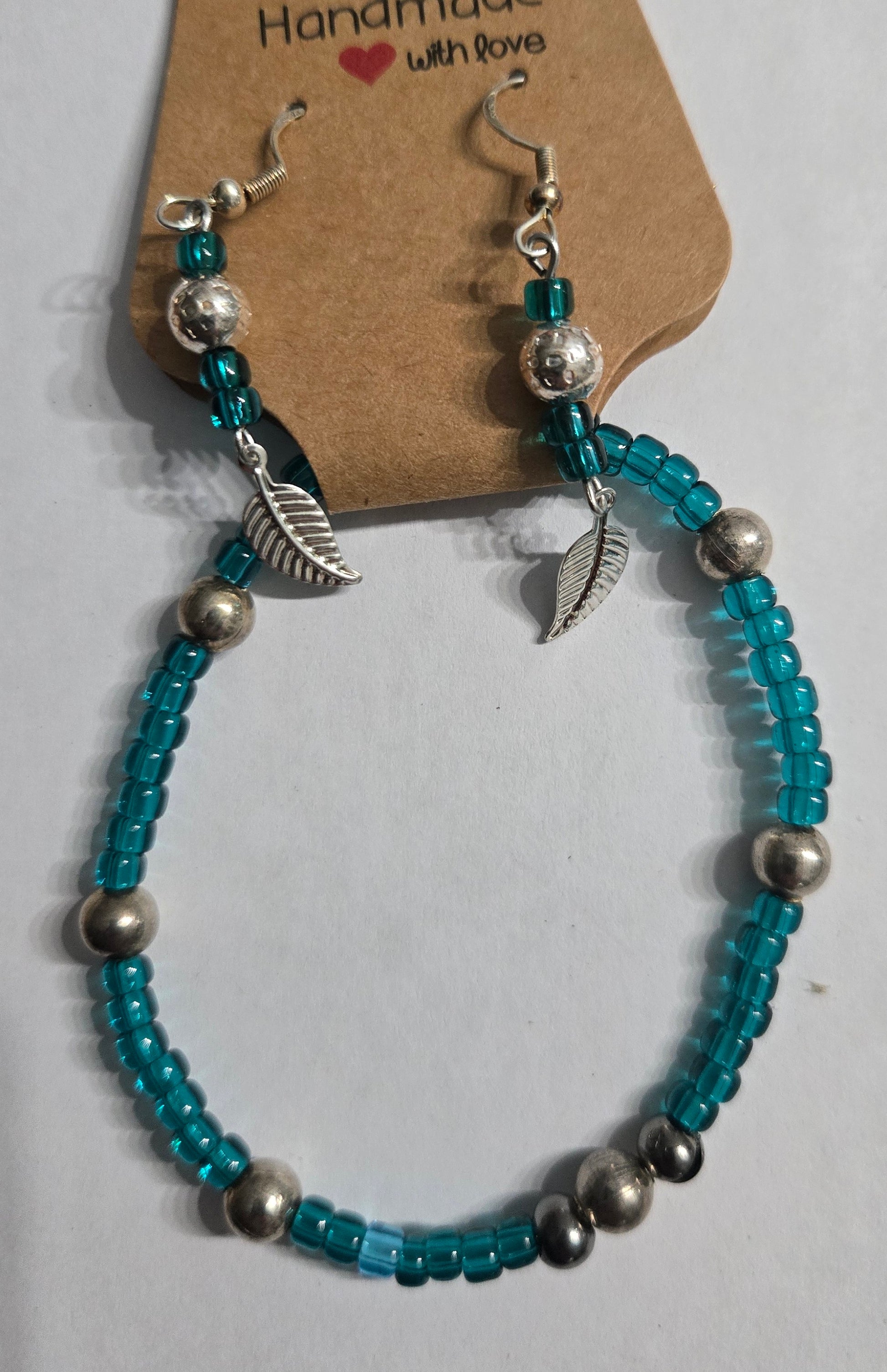 Beaded bracelet and earrings with leaf charms and silver in color round beads.