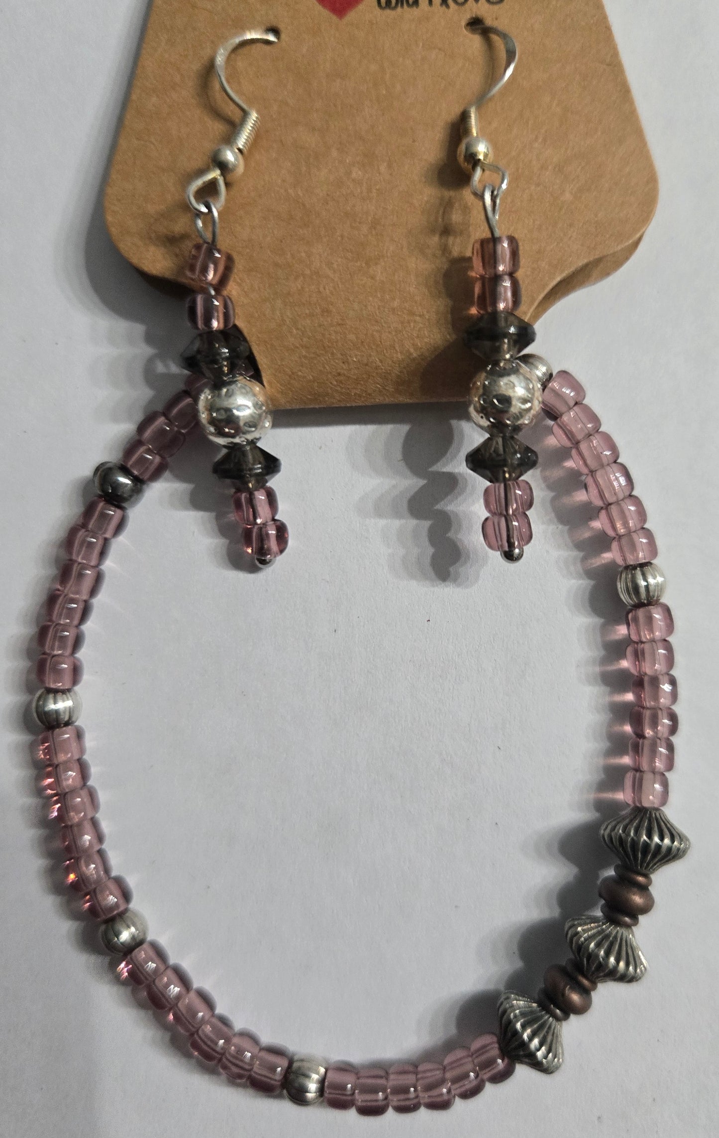 Bracelet made with translucent purple beads, accented with silver in color charms + matching earrings.