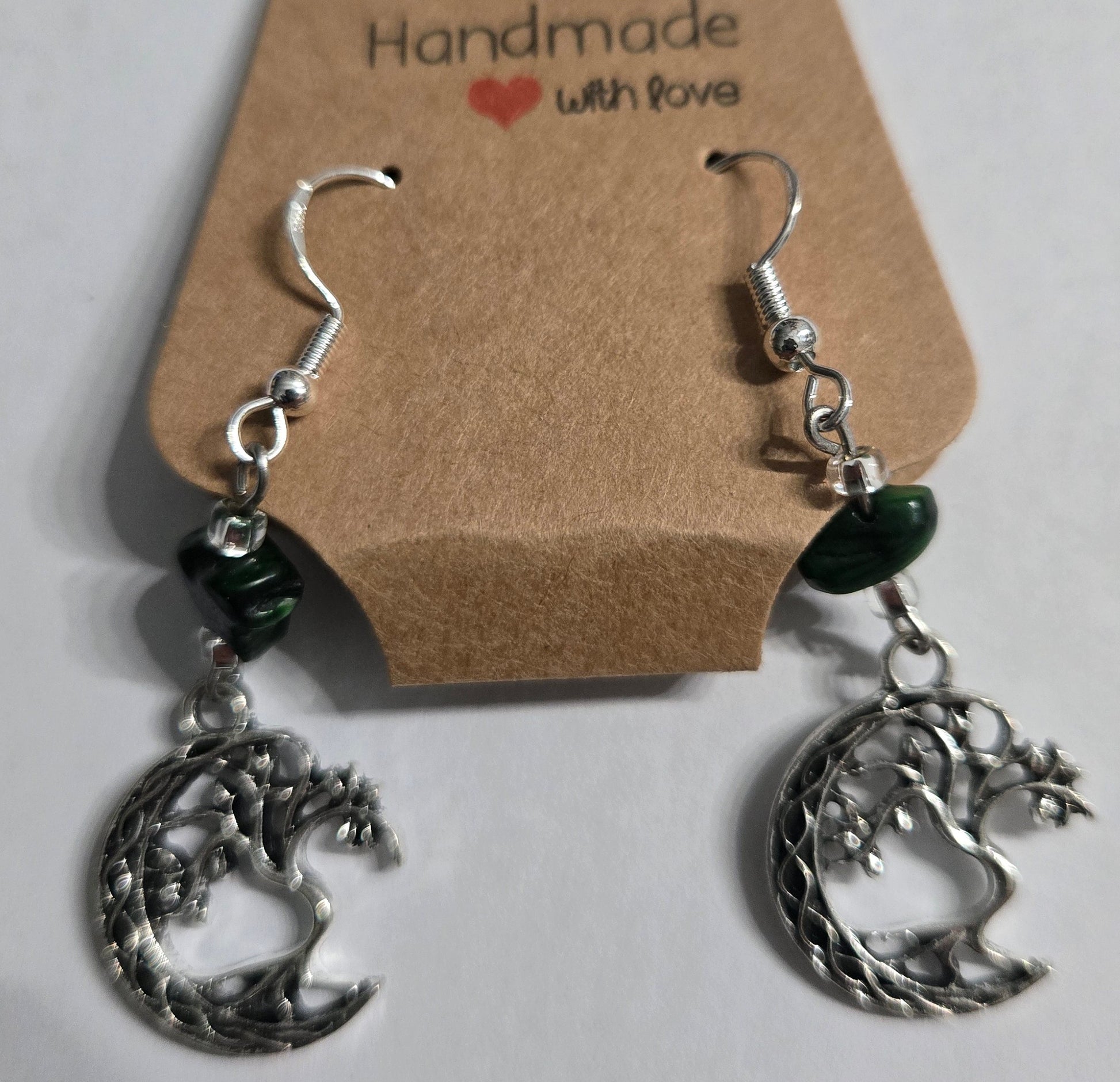Hand crafted sterling silver earrings, accented with clear glass and green stone beads, with pewter "Tree of Life" charms.