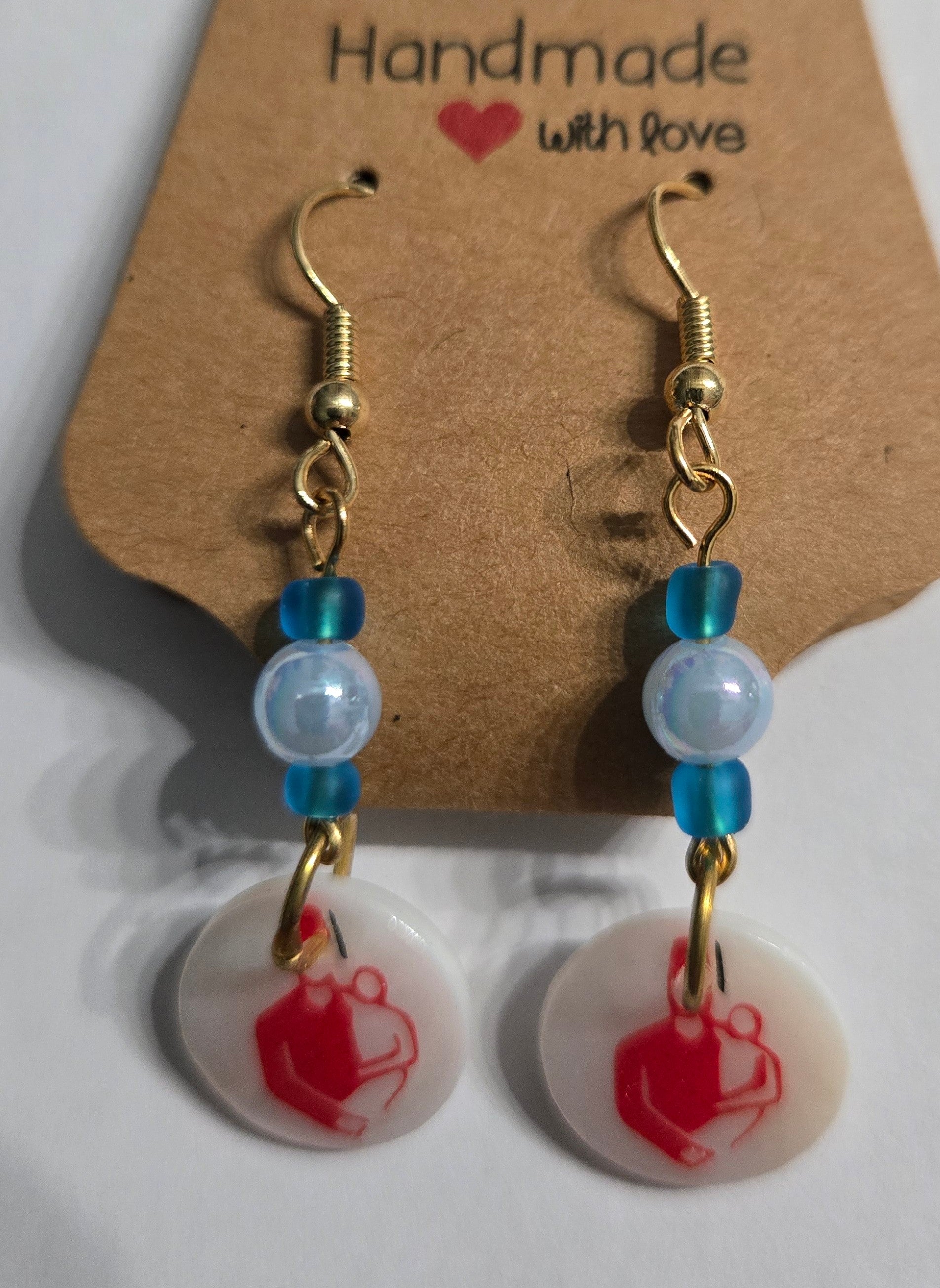 Gold plated earrings with blue and light blue beads, accented with white charms and the Shriner's Hospital logos.