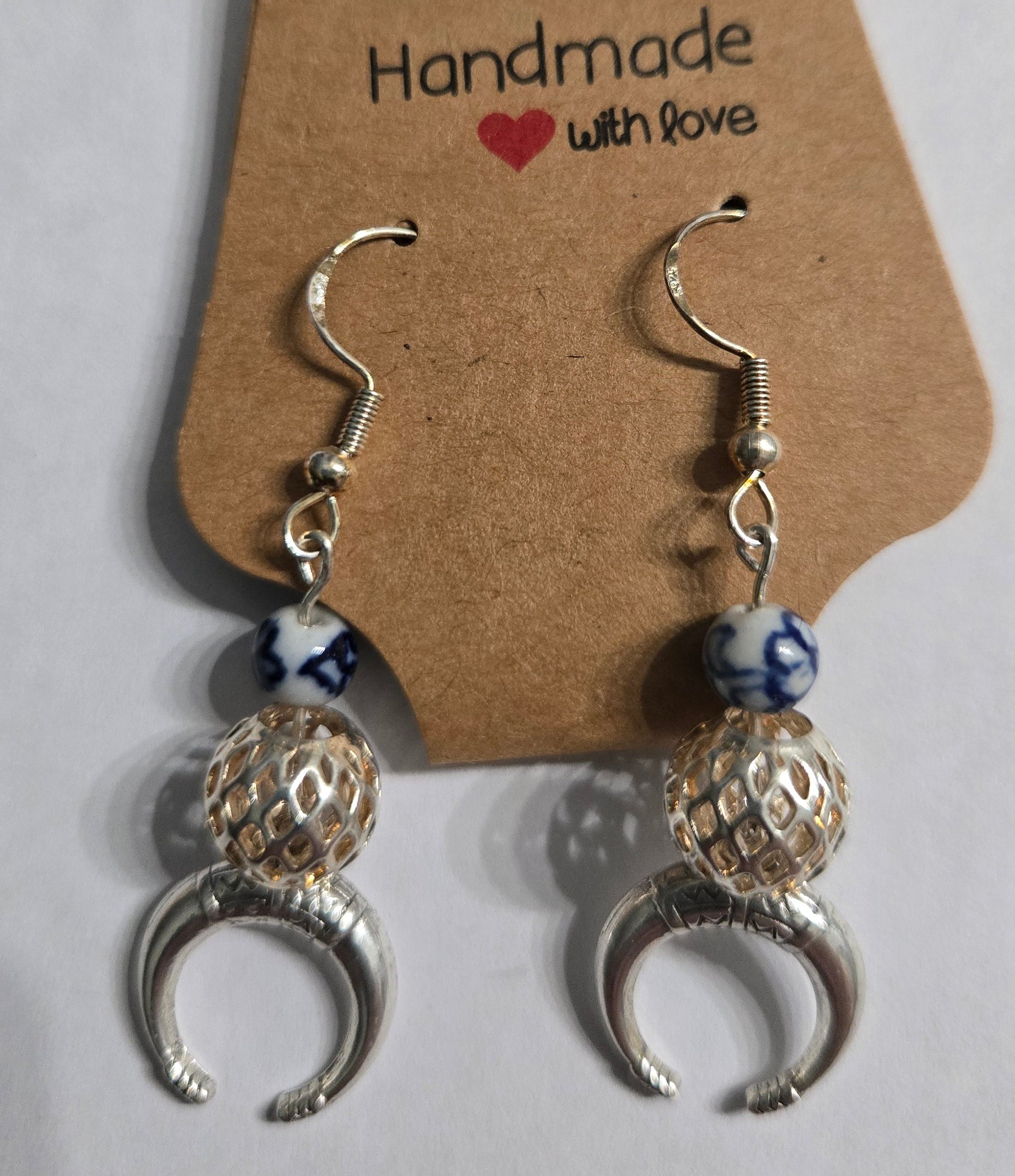 Sterling silver earrings with blue and white beads + silver in color perforated charms, accented with metallic silver crescent moon charms.