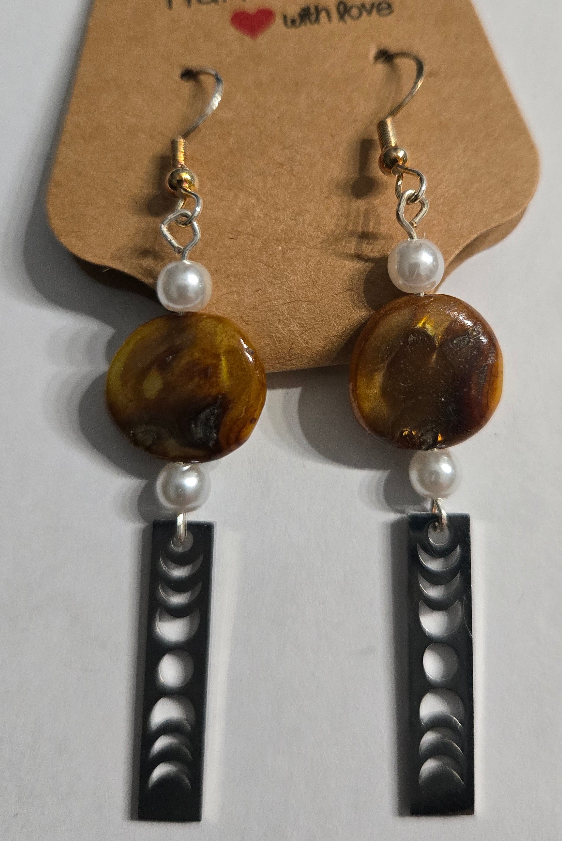 Pair of earrings with brown beads and moon phase charms, accented with faux pearls.