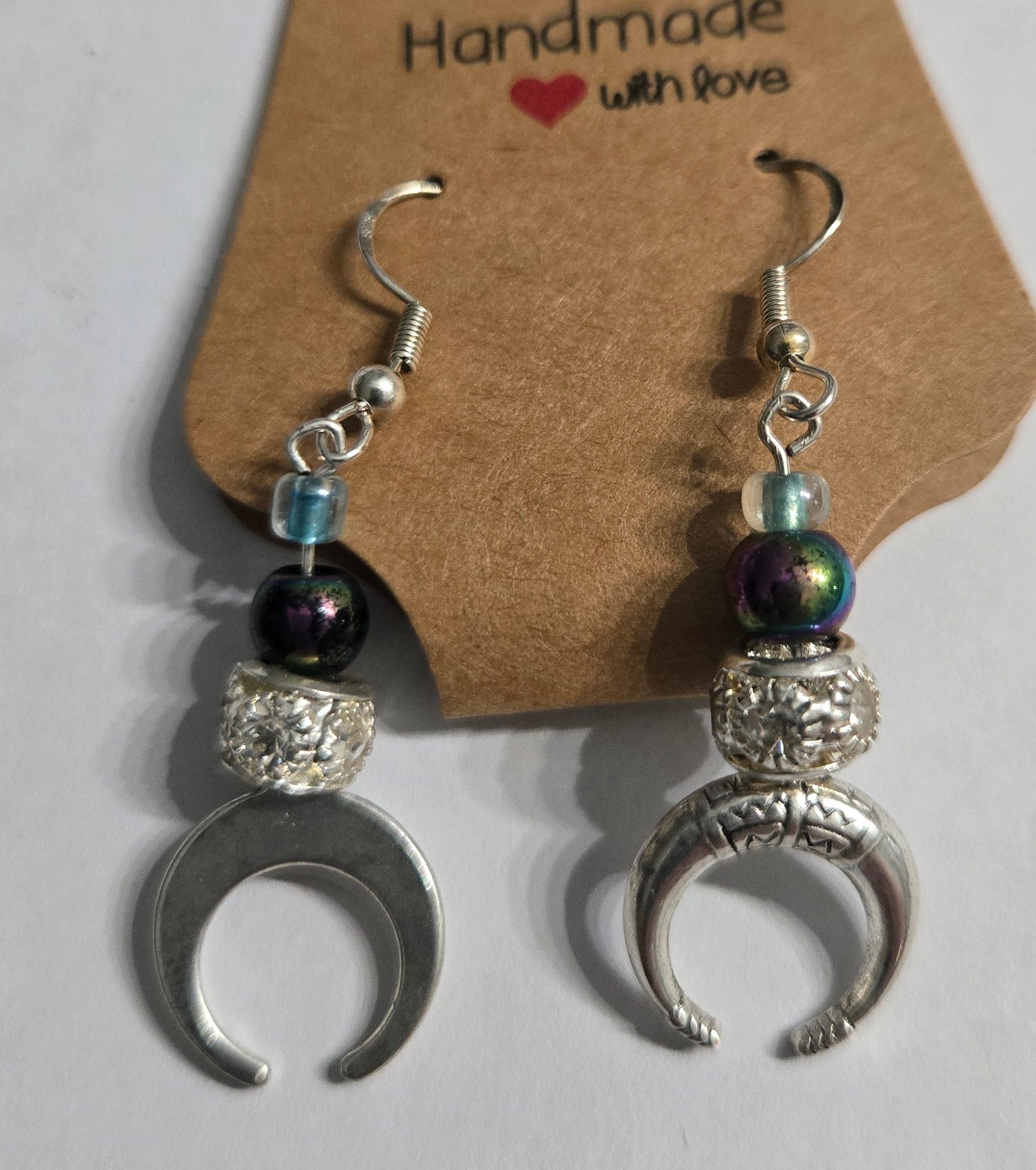 Pair of silver crescent moon earrings with holographic beads, small glass beads, and silver in color metallic beads encrusted with simulated CZ stones.