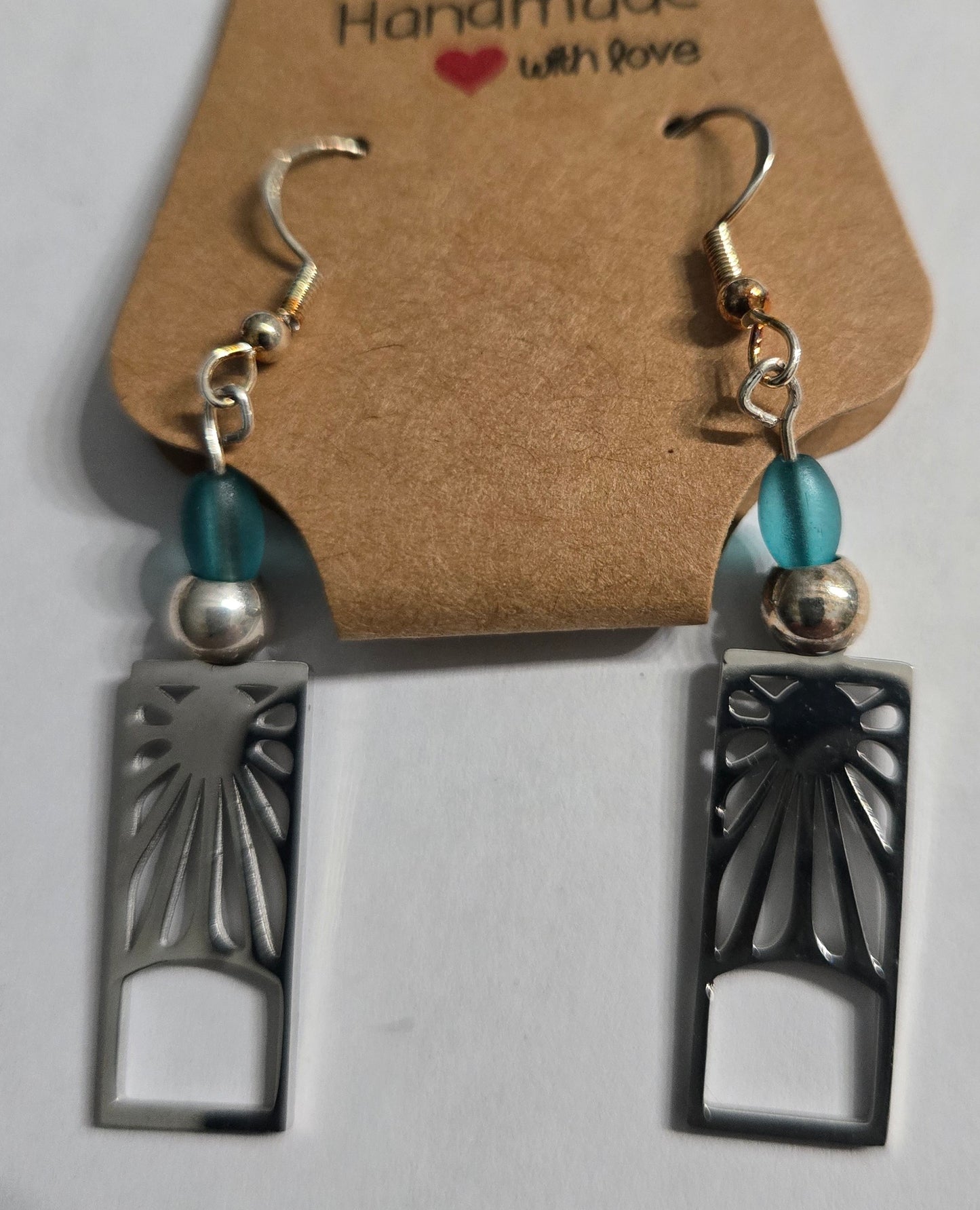 Handmade earrings with pewter sun charms, accented with blue glass beads, and crafted on sterling silver earring facets.