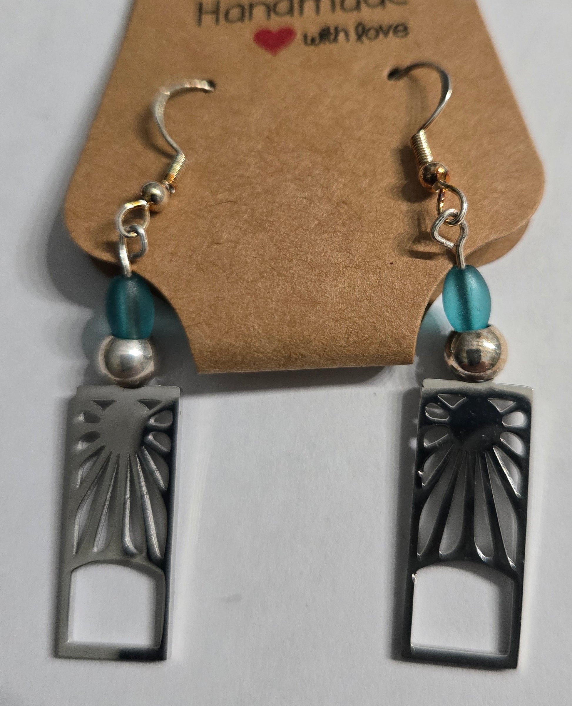 Handmade earrings with pewter sun charms, accented with blue glass beads, and crafted on sterling silver earring facets.