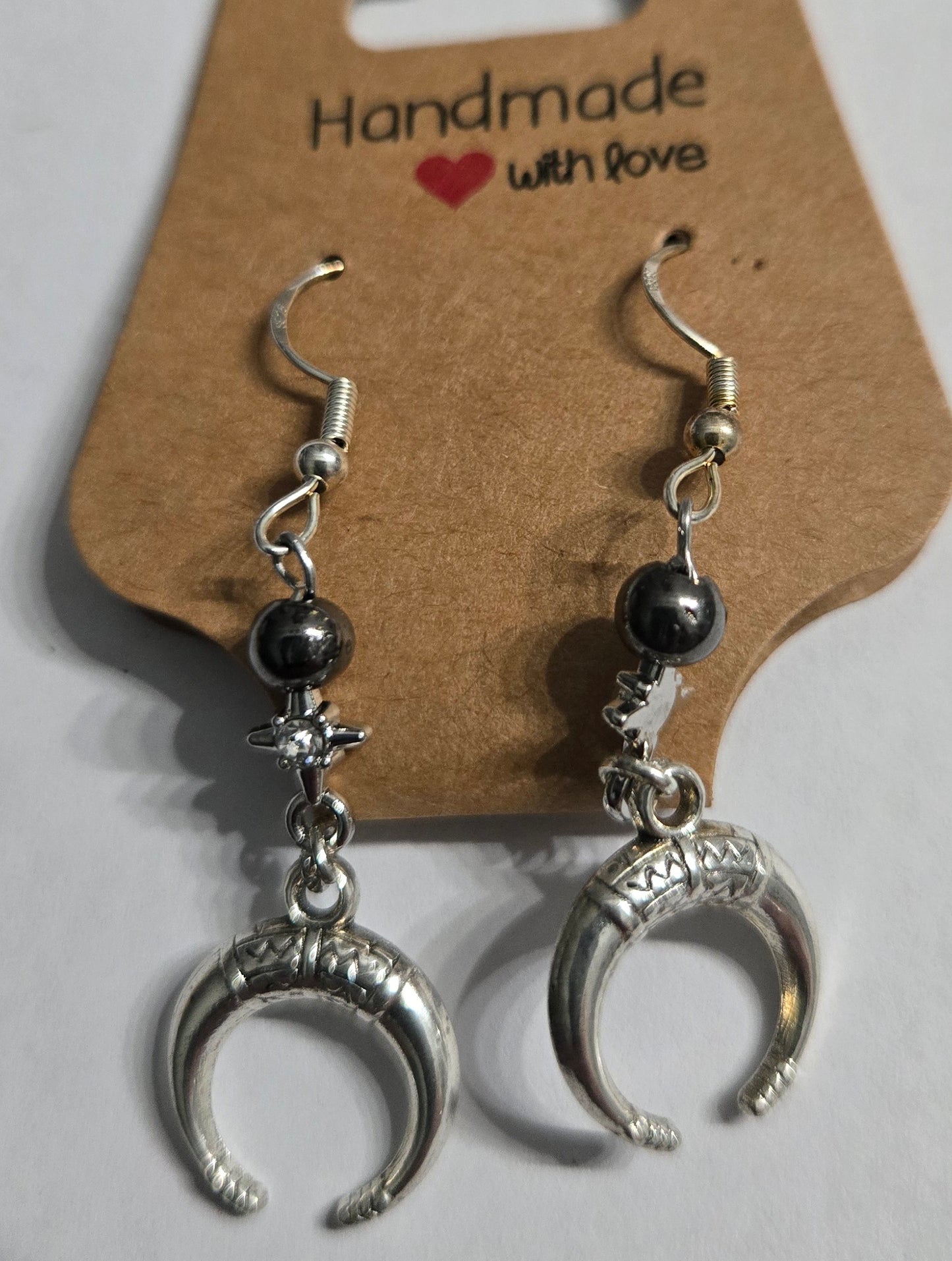 Silver in color crescent moon earrings with metal beads, accented with metallic stars encrusted with CZ simulated diamonds. 