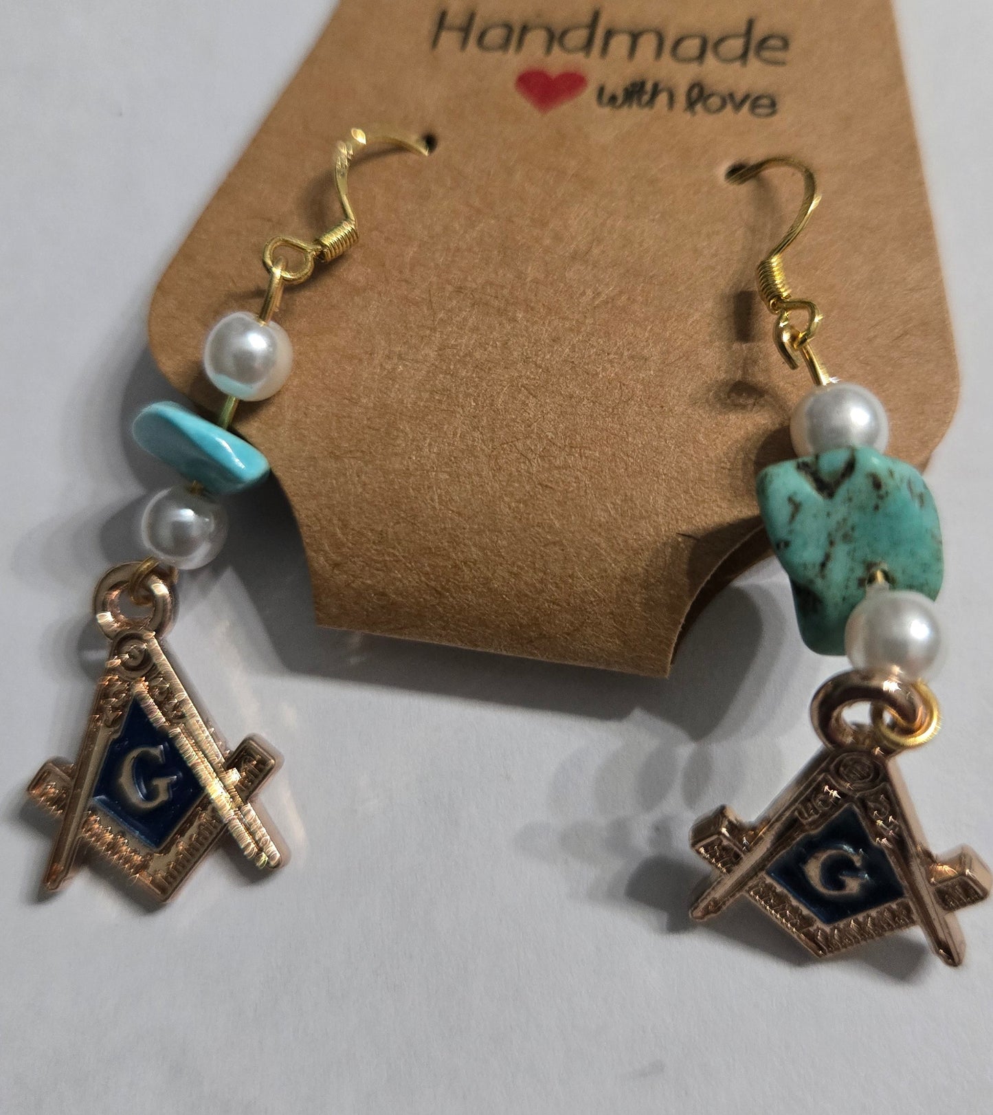 Handmade Masonic earrings with gold in color Masonic charms, accented with turquoise and faux pearl beads, and crafted on gold plated earring facets.