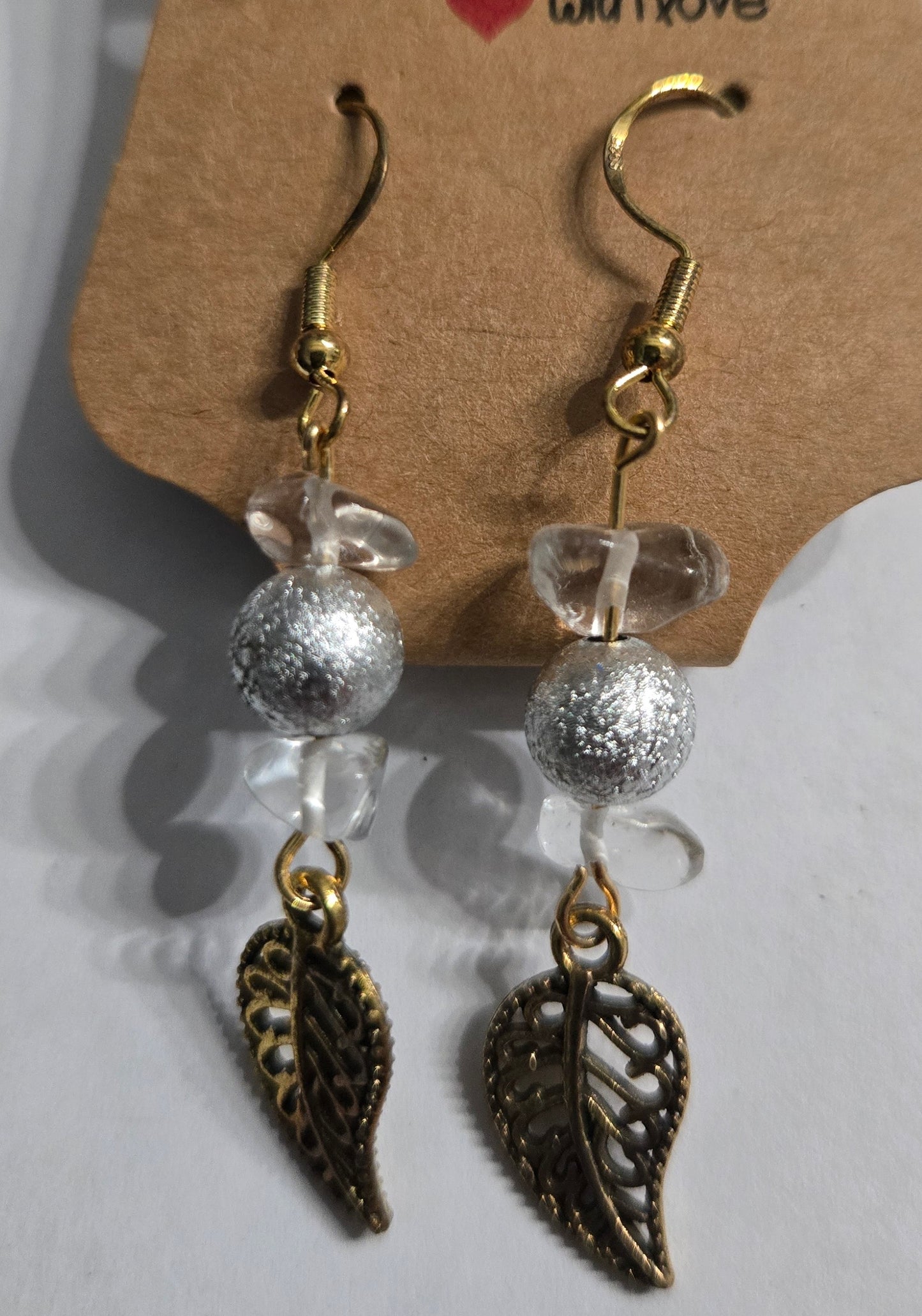 Gold plated earrings with silver / clear beads, accented with brass leaf charms.