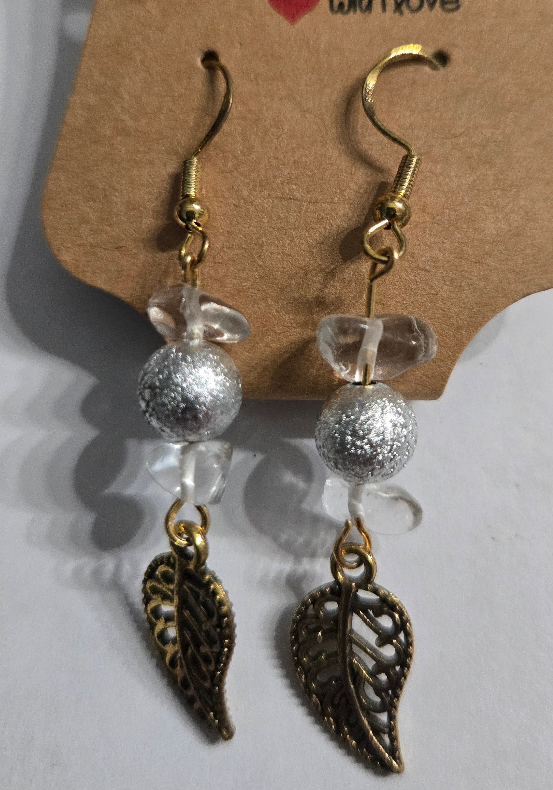 Gold plated earrings with silver / clear beads, accented with brass leaf charms.
