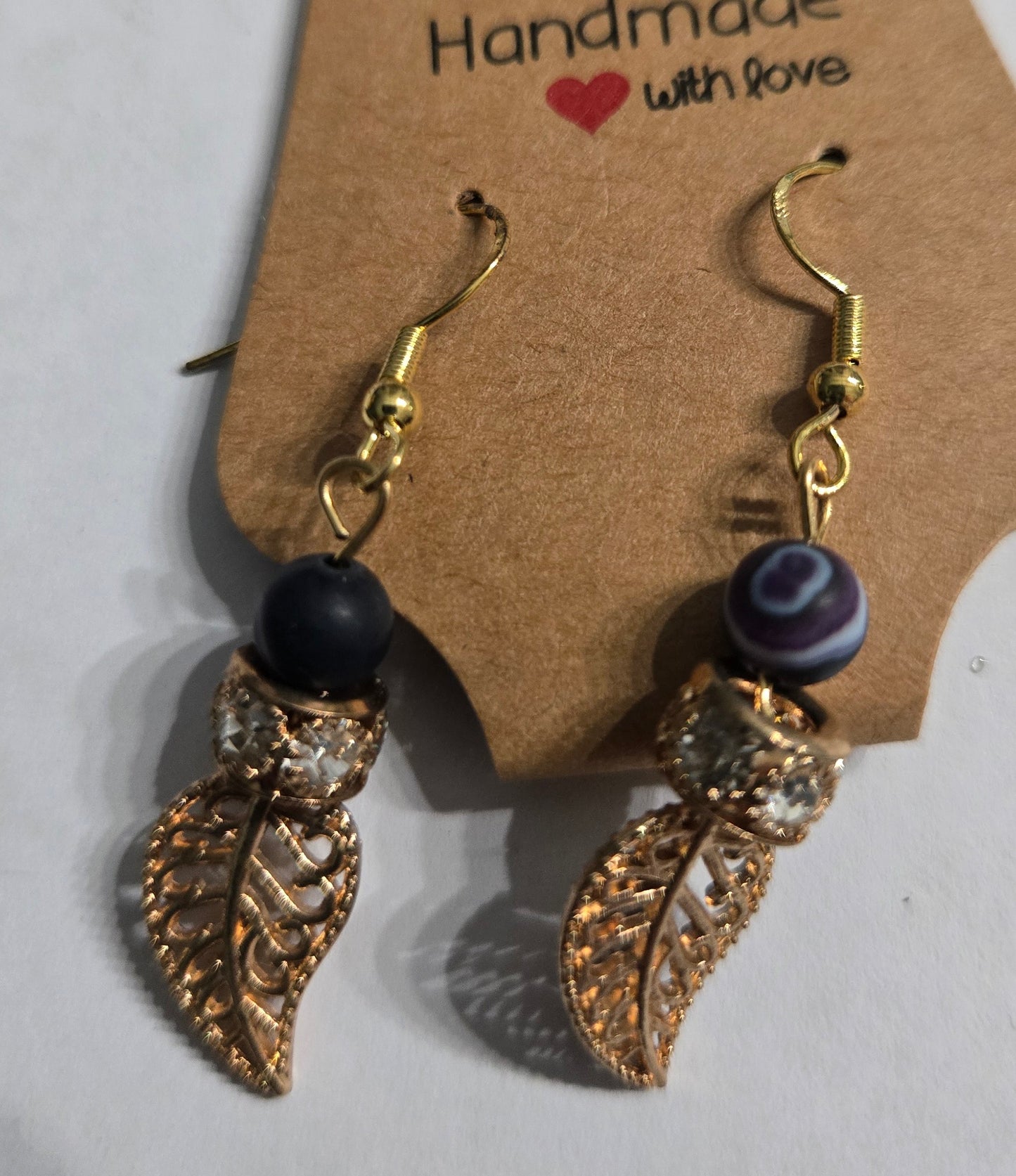Gold plated earrings with purple / blue beads, accented with gold metallic leaf charms and CZ simulated diamond stones.