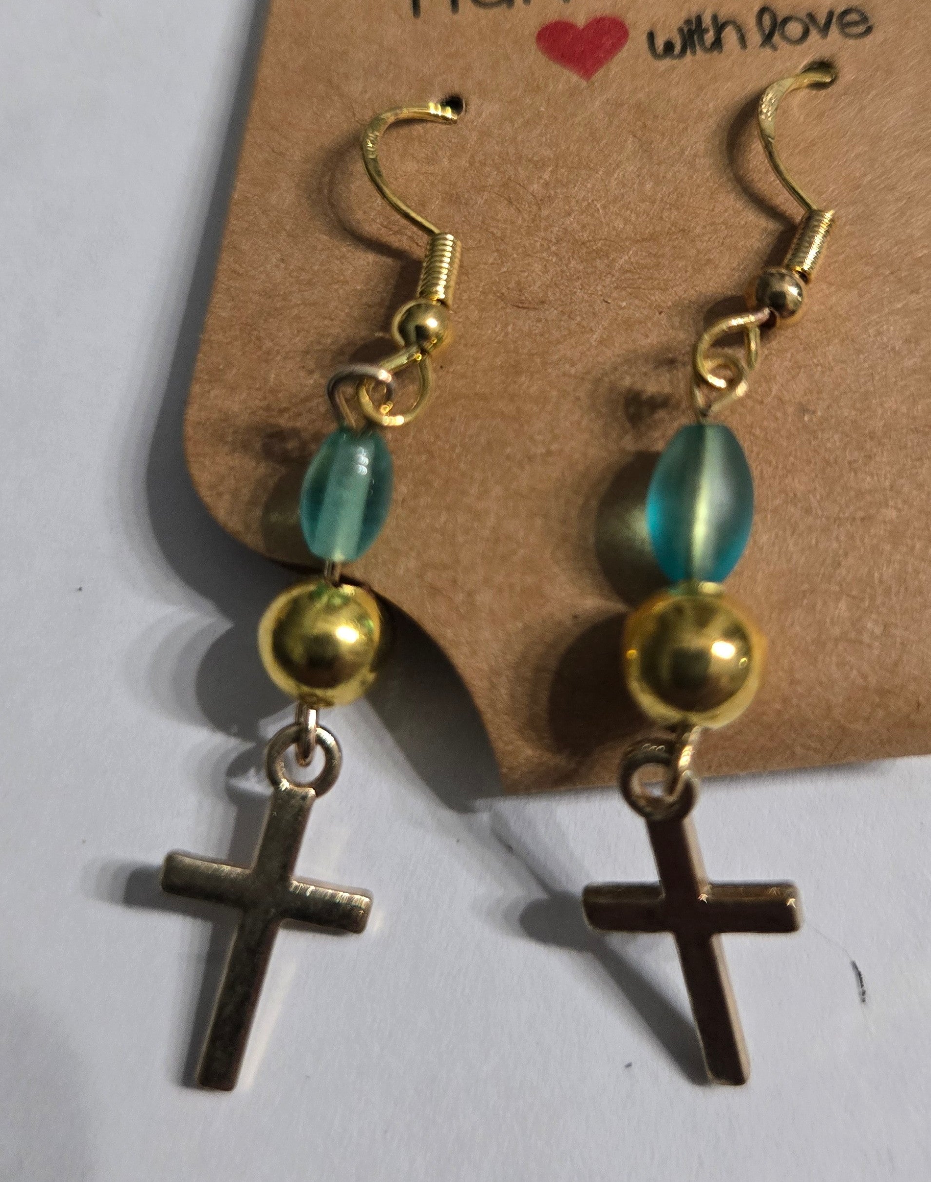 Gold plated earrings accented with blue and gold metallic beads, and gold metallic cross charms.