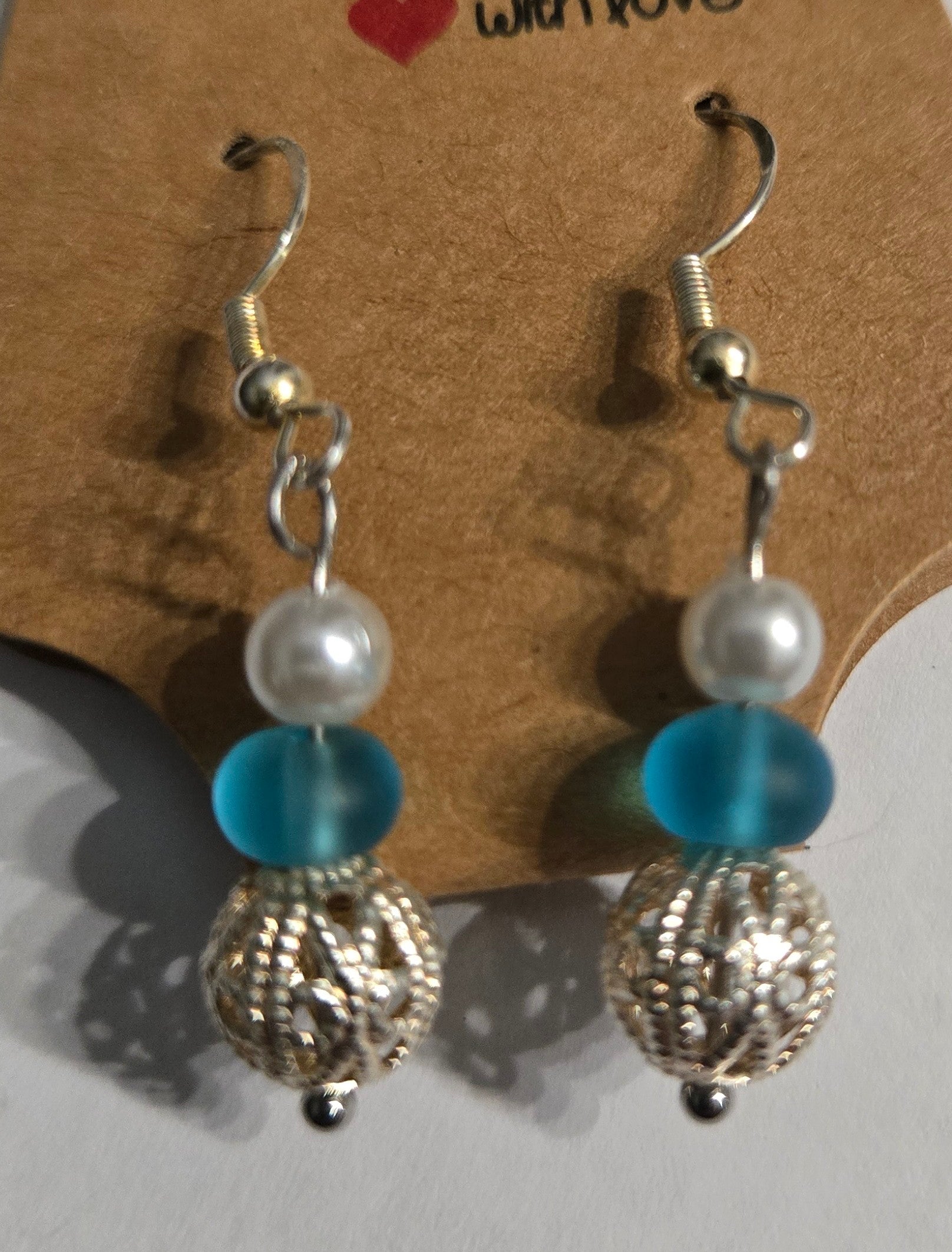 Sterling silver earrings with round blue and faux pearl beads, accented with silver metallic charms.