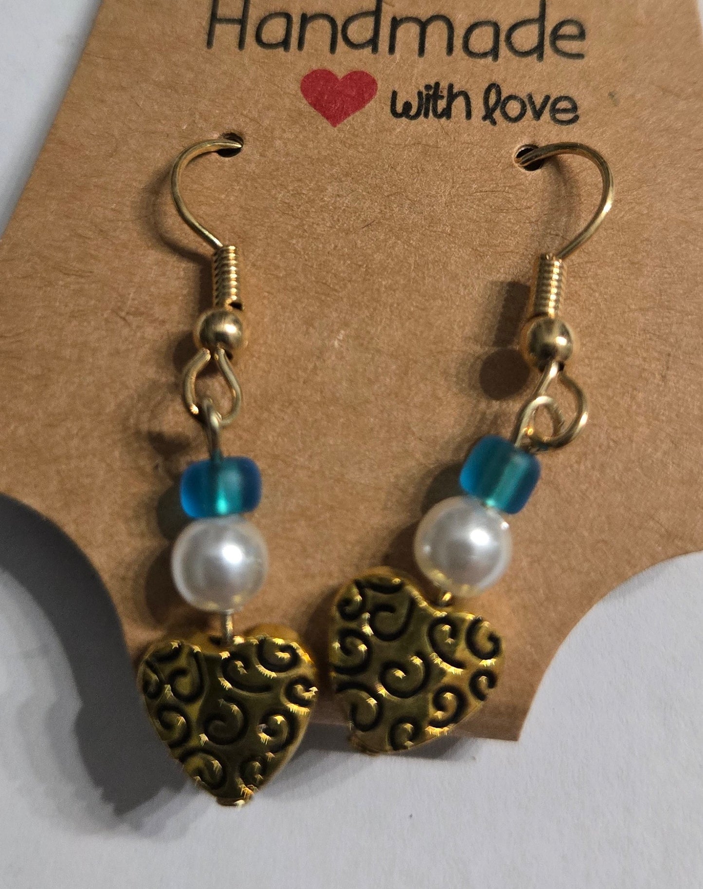 Gold plated earrings with round blue and faux pearl beads, accented with gold metallic heart charms.