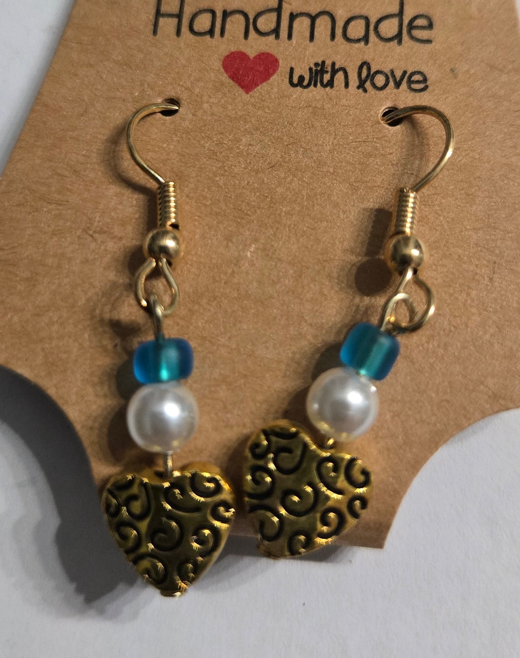 Gold plated earrings with round blue and faux pearl beads, accented with gold metallic heart charms.