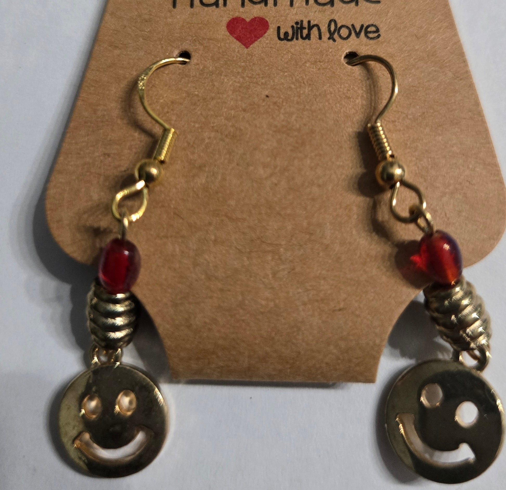 Gold plated earrings with round amber beads, accented with gold metallic smiley face charms.
