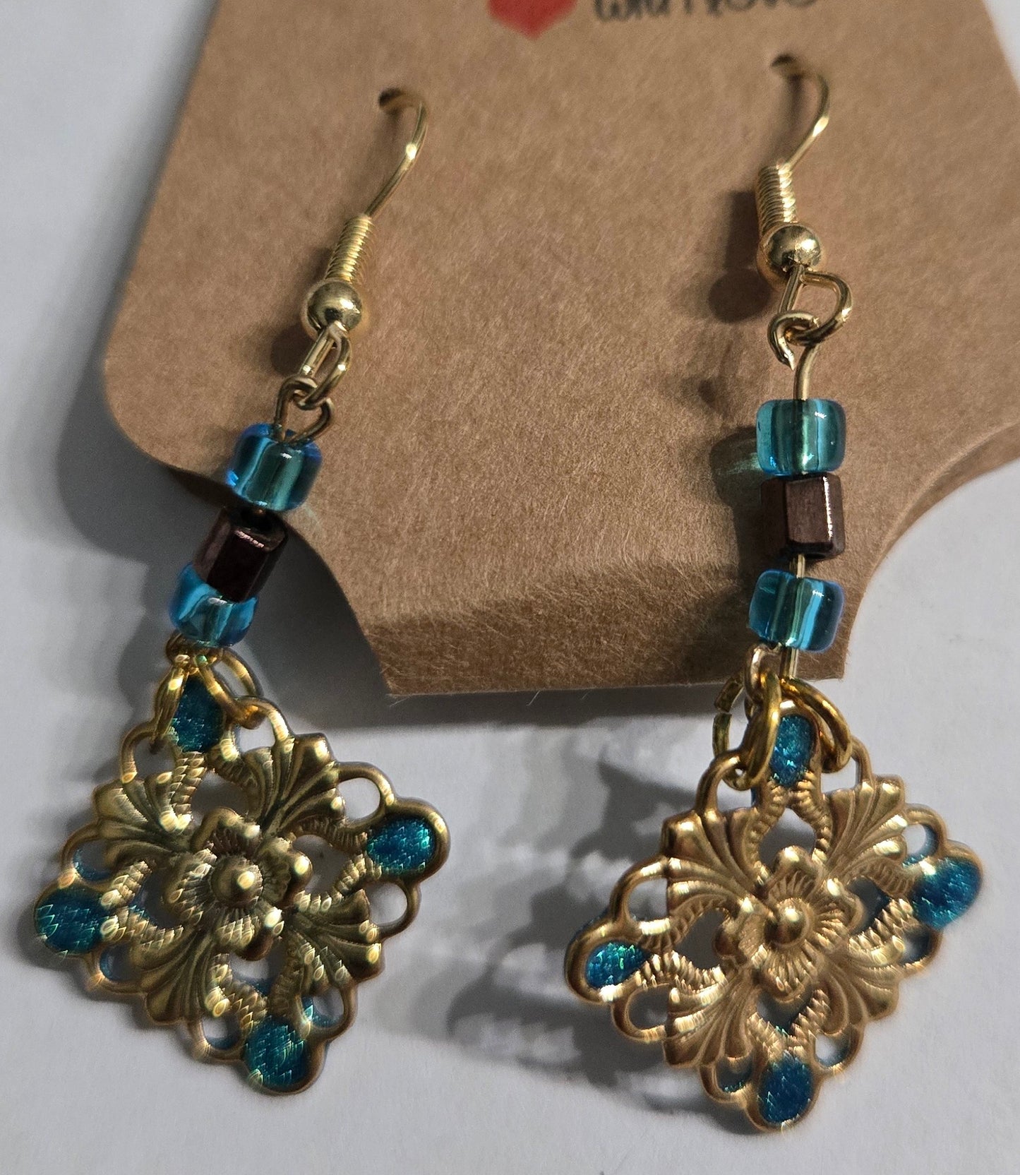 Gold plated earrings with blue glass beads, accented with gold metallic charms with blue epoxy resin inlay.