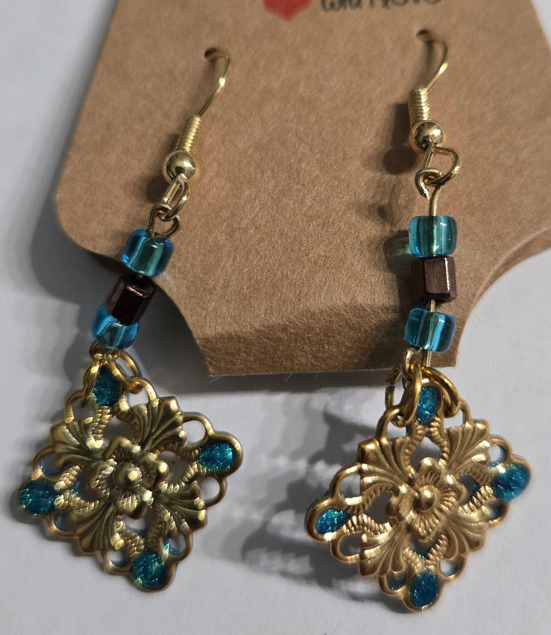 Gold plated earrings with blue glass beads, accented with gold metallic charms with blue epoxy resin inlay.