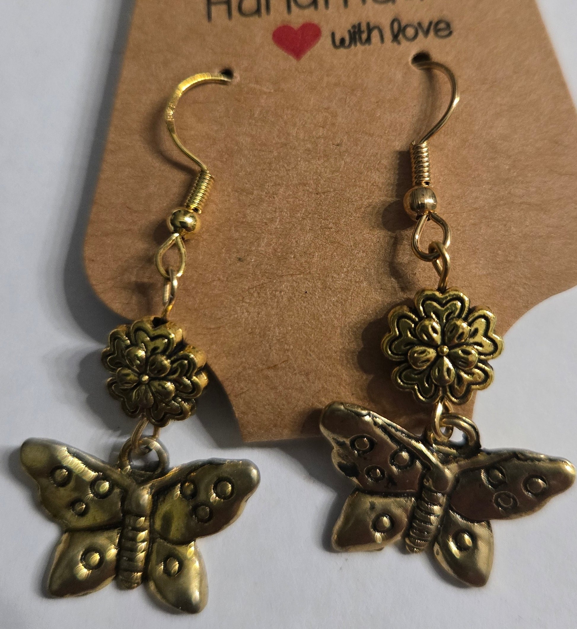 Gold plated earrings with gold metallic flower beads, accented with gold metallic butterfly charms.