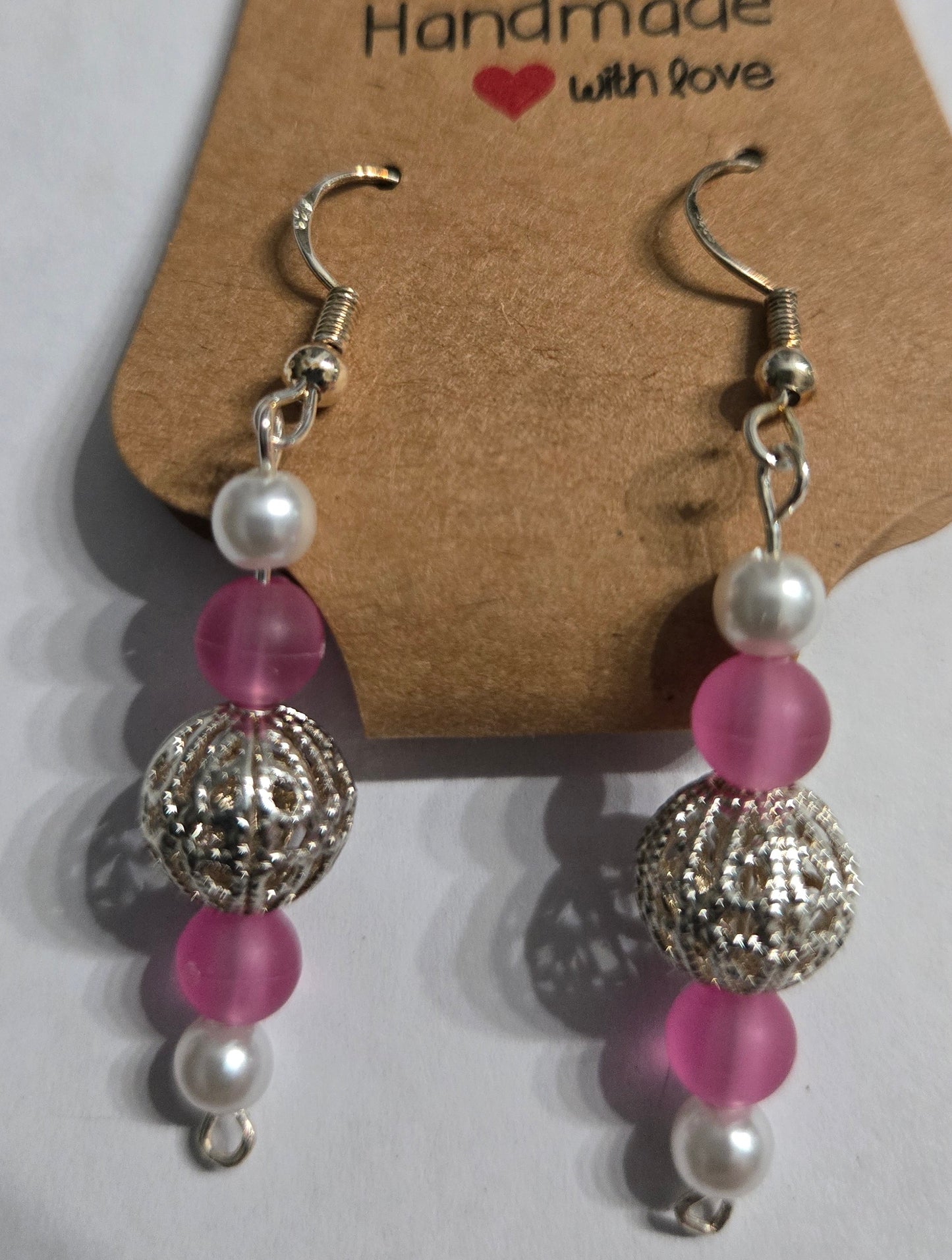 Sterling silver earrings with round faux pearl and pink beads, and a silver metallic filigree charm.