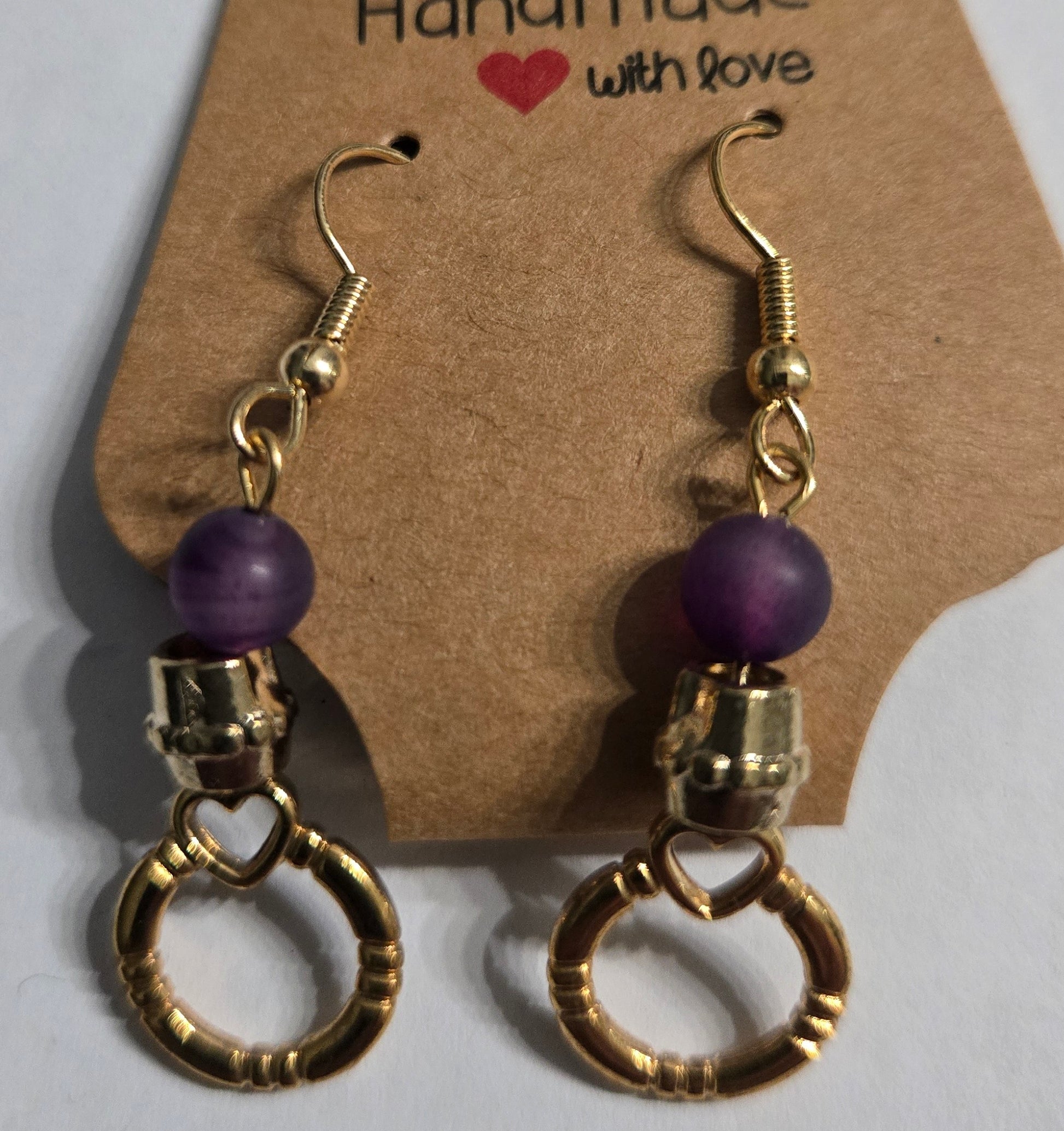 Gold plated earrings with purple beads, gold metallic accent beads, and gold metallic hoop charms.