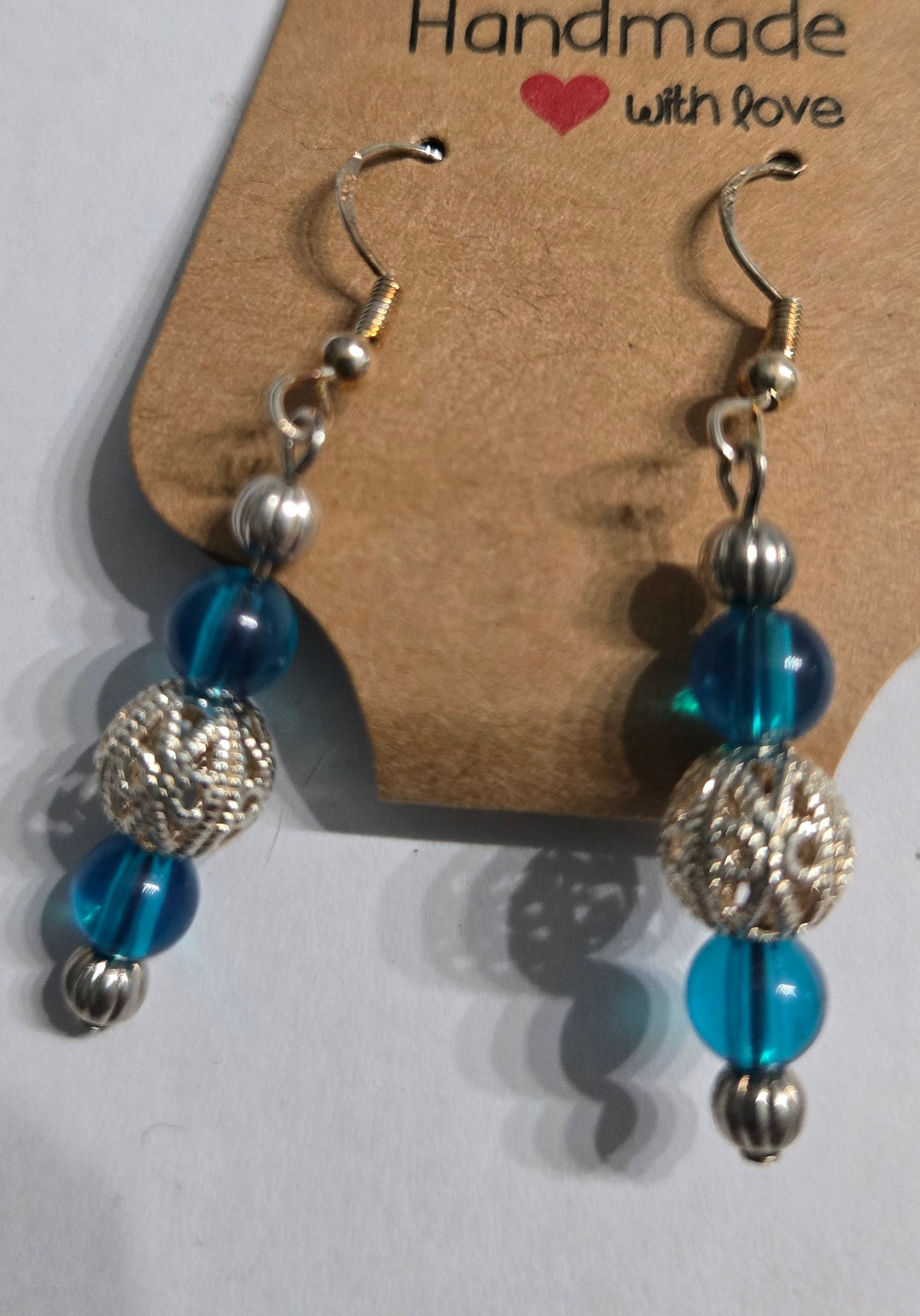 Sterling silver earrings with metallic silver and blue beads, accented with a filigree center charm.