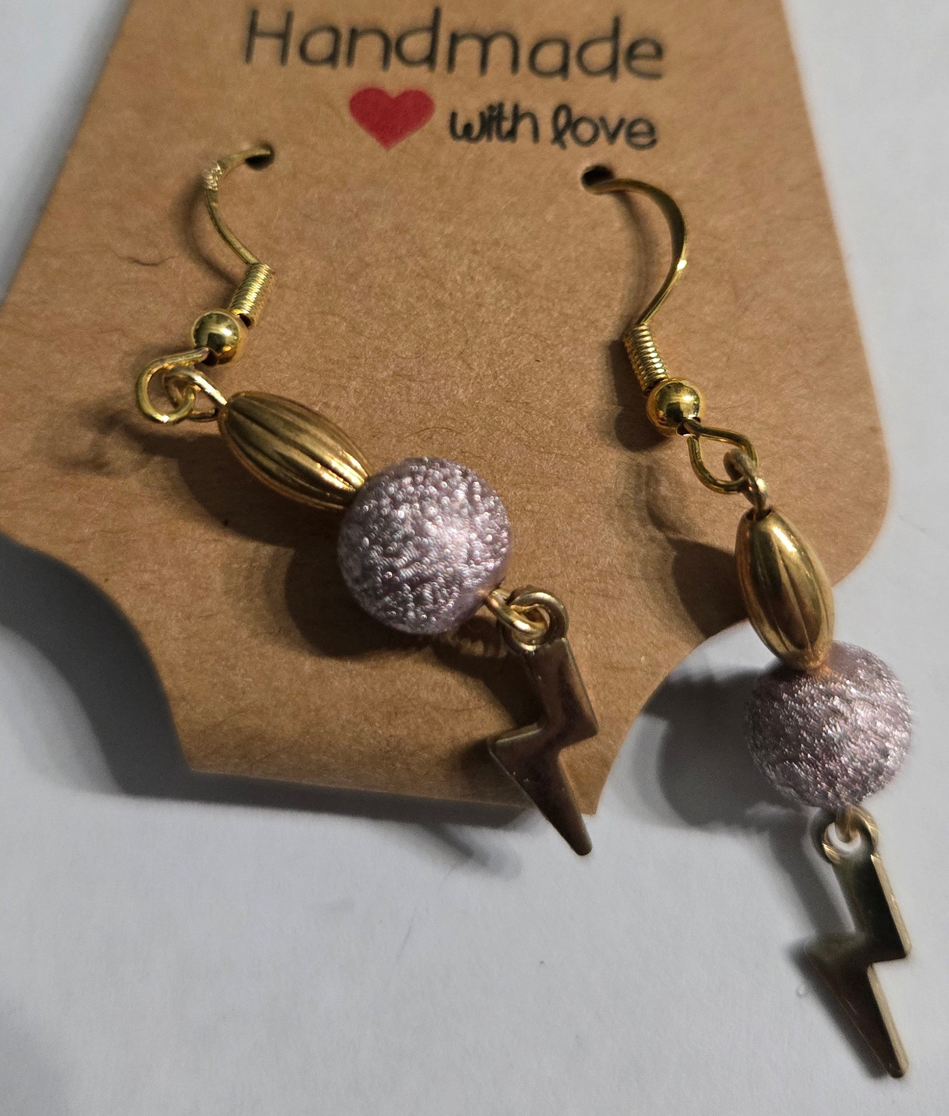 Gold metallic earrings with silver / gold metallic beads, and gold metallic lightning bolt charms.