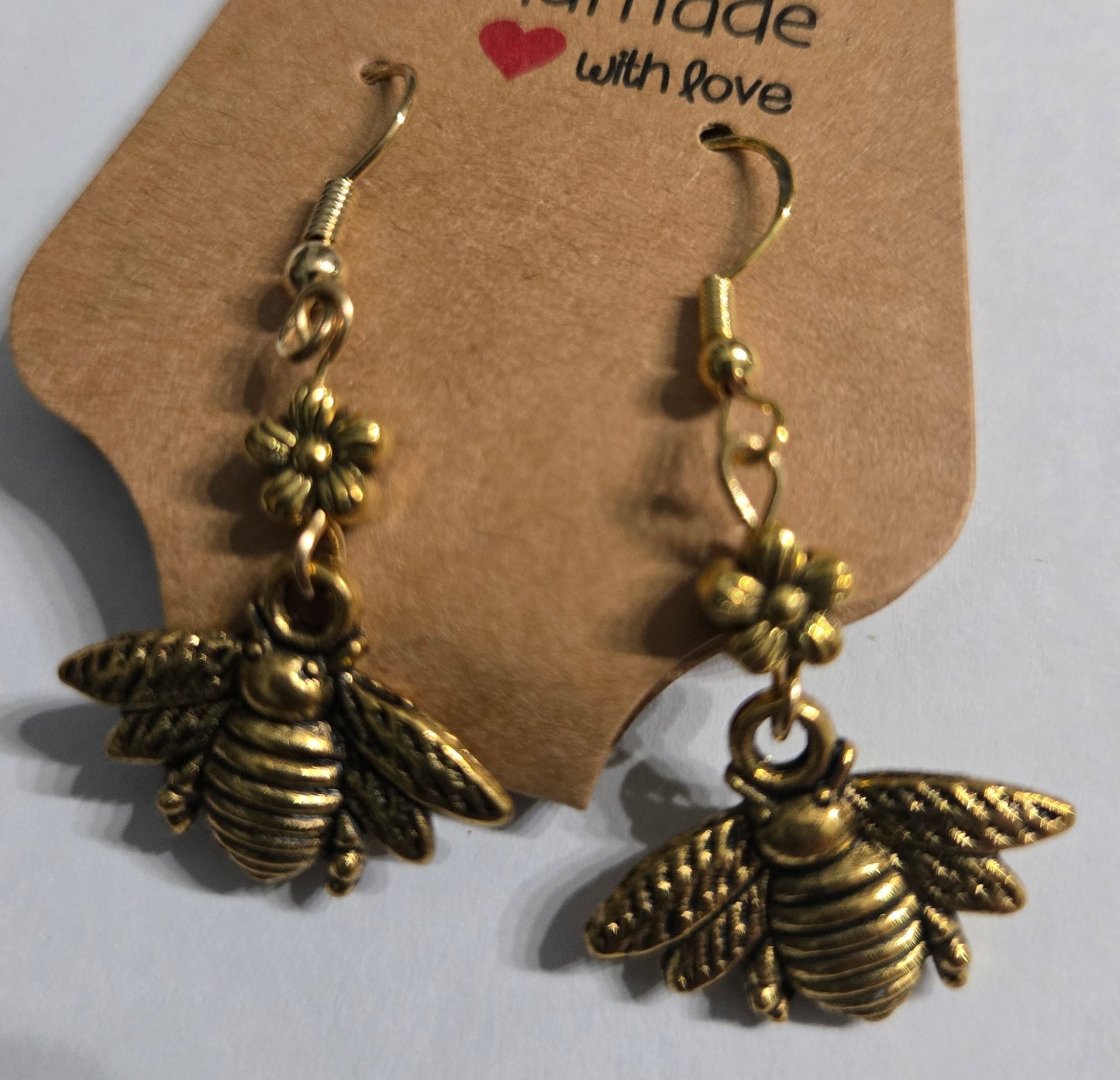Gold metallic earrings with gold metallic flower and beetle charms.